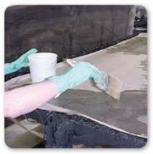 Vista de dos manos con guantes de goma pintando con una brocha una superficie plana